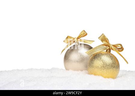 Beautiful golden Christmas balls with bows on snow against white background Stock Photo