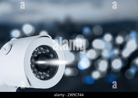 Modern security CCTV camera against blurred background, space for text Stock Photo