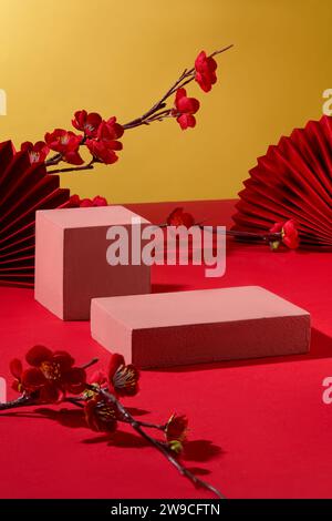 Two pink podiums are placed on a red-gold background. Peach blossom branches and paper fans are decorated around. Empty podium is suitable for product Stock Photo