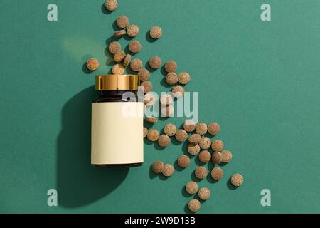 An unlabeled medicine bottle placed next to brown pills scattered on a dark green background for use in presentations,advertising, education manuals, Stock Photo