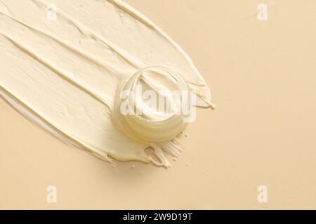 Flat lay of a unmarked jar streaks of cream with an pastel color texture are brushed against a pastel pink background. Facial creme, foam, gel or body Stock Photo