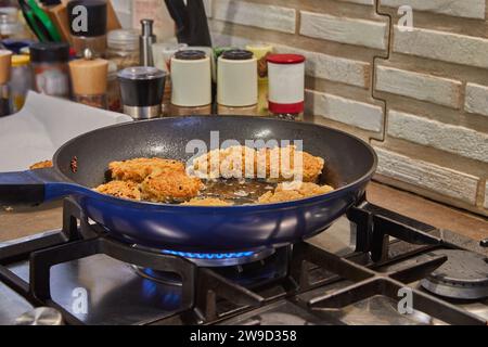 Freshly prepared swan cutlets sizzling in hot oil in a typical home kitchen. The golden brown cutlets are being fried to perfection, creating a mouth- Stock Photo