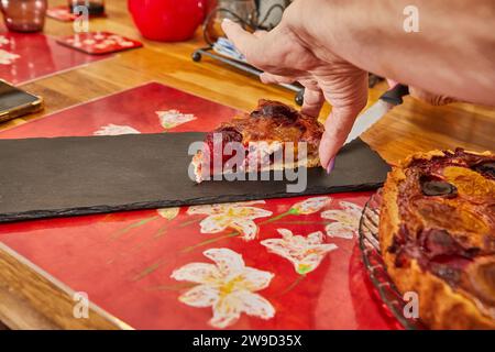 Slicing a delicious homemade plum pie baked in an electric oven, showing the golden crust and juicy plum filling, promising a delightful treat for any Stock Photo