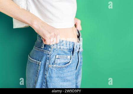 The girl is holding jeans that are too big. Weight loss concept. Stock Photo