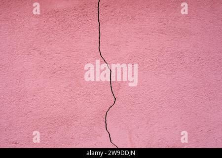 Pink plaster facade house wall with dark cracks. Texture for background. Stock Photo