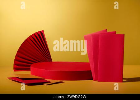 Empty red podium decorated with red paper fan and several envelopes in yellow and red color. Mock-up for exhibitions or presentation of cosmetic produ Stock Photo