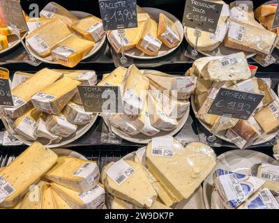 Italy - December 24, 2023: Italian cheese of various kinds cut into slices packaged and priced on display in refrigerated counter for sale in Italian Stock Photo