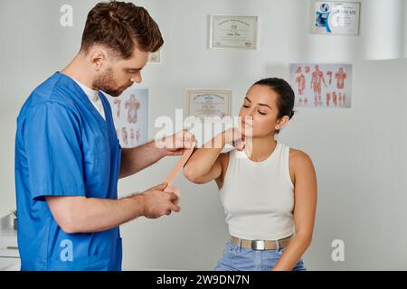 Professional Doctor Putting Kinesiological Tapes On Elbow Of His Female ...