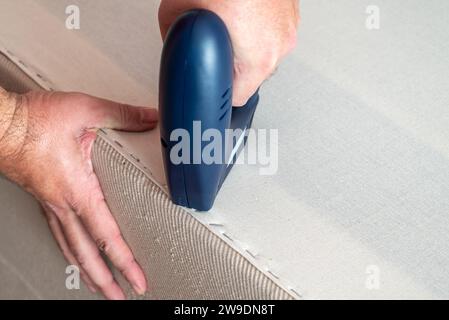 Worker stapling sofa lining with electric staple gun Stock Photo