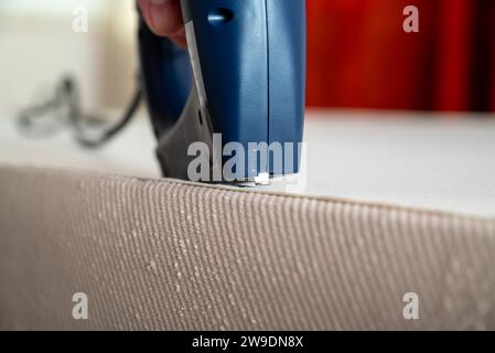 Worker stapling sofa lining with electric staple gun Stock Photo