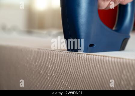 Worker stapling sofa lining with electric staple gun Stock Photo
