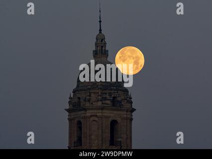 Malaga, Spain. 27th Dec, 2023. The full moon of December, known as the 'cold moon', is seen in the sky behind Malaga cathedral. In December takes place the last full moon of the year and the first of winter, called the cold moon due to the cold temperatures of winter in the Northern Hemisphere. Credit: SOPA Images Limited/Alamy Live News Stock Photo