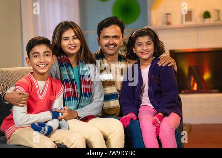 Indian happy family in winter wear looking camera at home while spending time together - concept of family bonding, holiday gathering and leisure Stock Photo