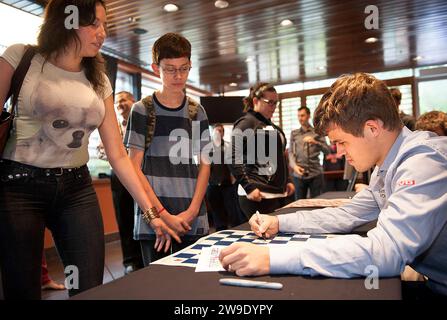 8 SEPT. 2013 -- ST. LOUIS -- Norwegian chess grandmaster Magnus Carlsen (right) signs autographs for Isaac Adams (center) and his mother Dora Jara, wh Stock Photo