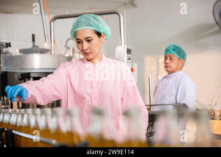 QC engineers inspect fruit juice drink production in glass bottles at the factory Stock Photo