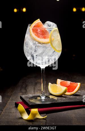 Gin tonic cocktail with grapefruit and ice on dark wooden background Stock Photo