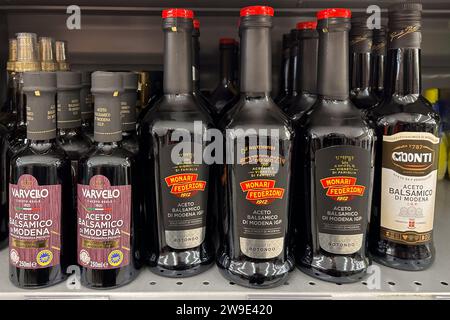 Italy - December 24, 2023: Balsamic Vinegar of Modena in glass bottles of various types and brands displayed on shelf for sale in Italian supermarket Stock Photo