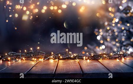 Christmas - Defocused String Light On Rustic Wooden Table In The Night With Abstract Tree Stock Photo