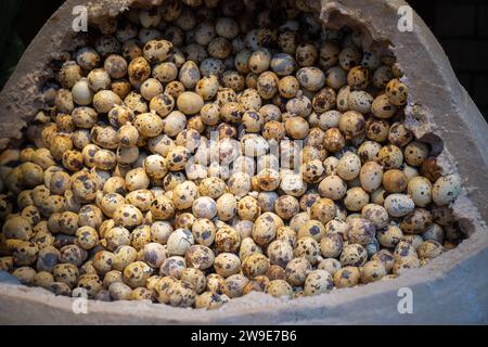 A close-up of fresh speckled quail eggs arranged in a large bowl at a market in Wuchang , China. Ideal for cooking and nutritional content. Stock Photo