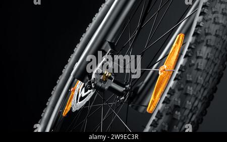 Front wheel of a new mountain bike close up on a black background. Studio shot. Professional sport equipment. Stock Photo