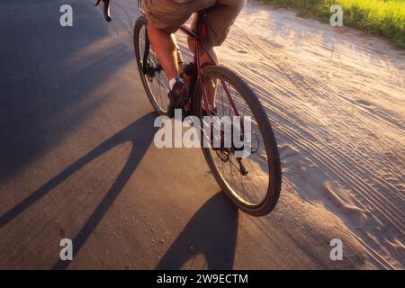 Cyclist rides on the road at sunset. View from above Active lifestyle concept. Stock Photo