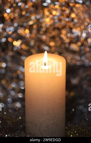 Close-up of a beautiful bright pillar candle against golden shimmering background Stock Photo