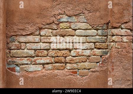 Bricks exposed from red plaster that has fallen away on a wall in Venice Italy. Stock Photo