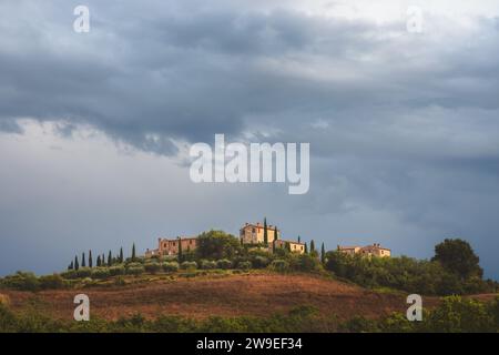 Moody, atmospheric light and dark dramatic sky over lone rustic stone farmhouse in the scenic countryside landscape of rolling hills and farmland of r Stock Photo