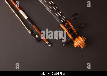 Detail of peg box and neck of traditional stringed violin and bow on isolated gradient black background.. Top view. Stock Photo