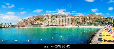 Anfi del Mar Resort, Gran Canaria: Summer day panoramic view of turquoise waters, beach, resort architecture, and beach chairs lining the shore Stock Photo