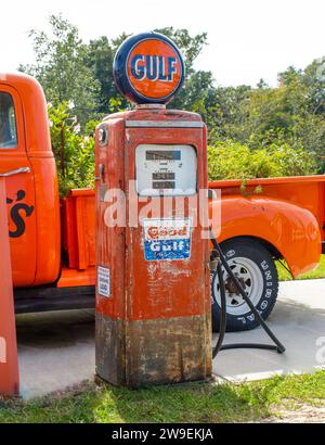 Ocala, Florida November, 2023 old orange gas pump by good gulf company brand logo next to old Chevy Chevrolet pickup truck with uniroyal rubber tires. Stock Photo