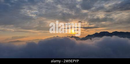 A stunning landscape featuring a vibrant sunrise over a mountainous backdrop Stock Photo