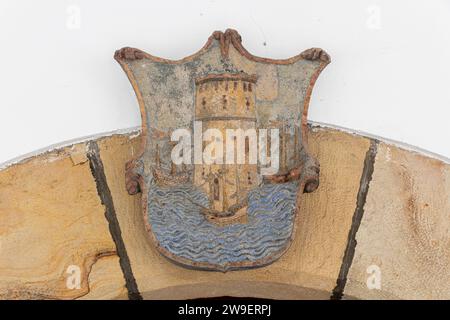 Laredo, Spain. Coat of arms of Laredo in the town Hall in the Old City, with the ships and the Sevilla Torre del Oro Stock Photo