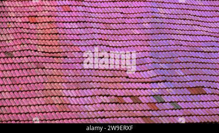 A wavy roof with old tiles. Everything in good condition. The color of the shingles is changed to pink to created a gradient pink background Stock Photo