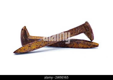Two railroad or rail road spikes crossed showing different angles isolated on white background.  Full extreme detail throughout entire railway crutch Stock Photo