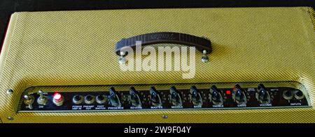 Old vintage retro style guitar tube amp or amplifier yellow tweed design Isolated on dark background. Control panel Volume , treble, bass, tone button Stock Photo