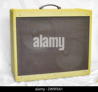 Old vintage retro style fender guitar tube amp or amplifier yellow tweed design with two large speakers visible behind brown grill cover plate.  Isola Stock Photo