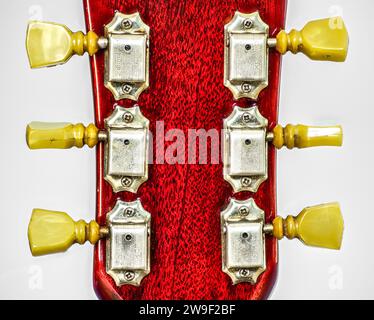 Closeup of guitar tuner or tuning pegs on red headstock.  Classic old school vintage kluson deluxe double ring circa 1966 on cherry color Gibson SG so Stock Photo