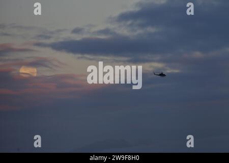 Bogota, Colombia. 27th Dec, 2023. December 27, 2023, Bogota, Colombia: General view of the last full moon of 2023, also known as the Cold Moon, is seen through the clouds at dawn over the city of Bogota. on December 27, 2023 in Bogota, Colombia. (Photo by José Isaac Bula Urrutia/Eyepix Group) Credit: Eyepix Group/Alamy Live News Stock Photo