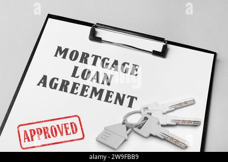Mortgage loan agreement with Approved stamp and house keys on table, closeup Stock Photo