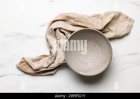 empty ceramic bowl and linen towel on light kitchen table, top view Stock Photo