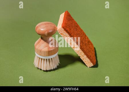 Wooden eco cleaning brush and coconut biodegradable sponge, eco cleaning tools on green background Stock Photo