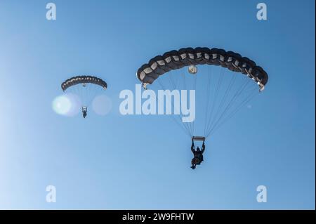 Pararescuemen, assigned to the 52nd Expeditionary Rescue Squadron, parachutes toward a landing zone after jumping from an HH-60 Pavehawk during training  at an undisclosed location in the U.S. Central Command area of responsibility, Dec. 15, 2023. Battlefield Airmen assigned throughout the  combined joint operational area conduct operations in support of Combined Joint Task  Force-Operation Inherent Resolve. (U.S. Air Force photo by Staff Sgt. Christian Sullivan) Stock Photo