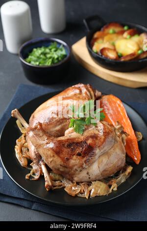 Tasty cooked rabbit meat with vegetables served on black table Stock Photo