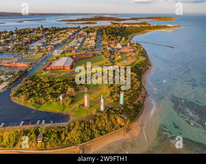 Aerial view of a lighthouse and towers on a green coastal reserve above the ocean at Queenscliff on the Bellarine Peninsula in Victoria, Australia. Stock Photo