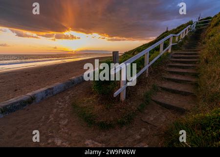 A colourful sunset over a set of steps down to a sandy beach at Queenscliff on the Bellarine Peninsula in Victoria, Australia. Stock Photo