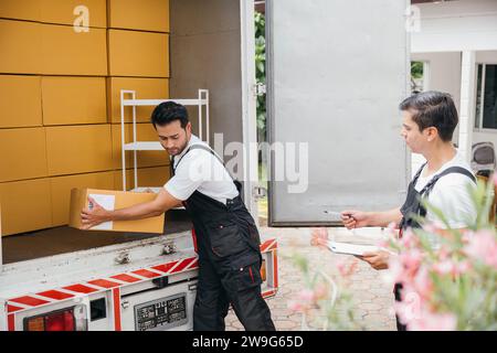 Two movers from a relocation company unload boxes exhibiting teamwork and dedication while Stock Photo