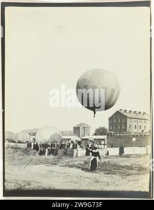 The Third Gordon Bennett Balloon Race, 1908 photograph Three half -blown balloons are still on the ground with the public around it. A balloon is already floating above the ground. In the background buildings. Schmargendorf baryta paper gelatin silver print balloon flight (sport). (flying a) gas balloon. balloon (aviation) Schmargendorf Stock Photo