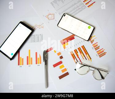 A still life photograph of everyday office supplies, including a cell phone, spread out on a polished desk Stock Photo