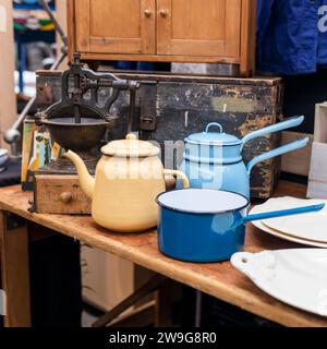 Yellow, blue and blue ladles and teapots against the background of an old coffee grinder in an antique market. Stock Photo